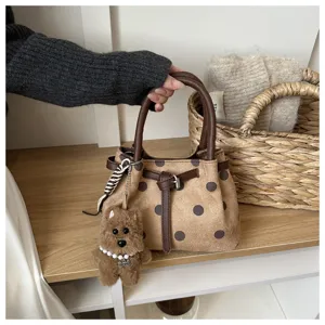 Detail van de stijlvolle gestippelde emmertas met bruine lederen handvatten en puppy hanger.