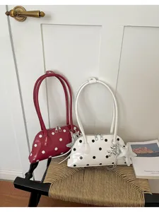 Stylish polka dot patent leather shoulder bag with long straps and cute charms for daily wear.