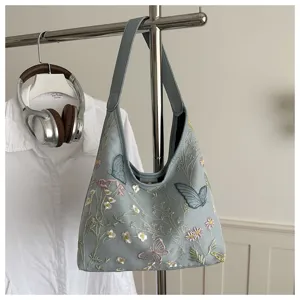 Hermoso detalle de bolso hobo azul claro con exquisito bordado floral y mariposas.