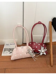 Detail view of stylish polka dot patent leather shoulder bag with chic silver star charm.