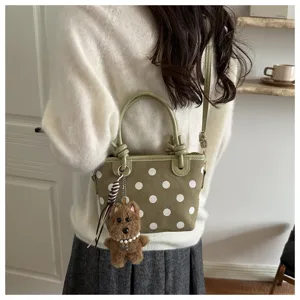 Vue detaillee du sac a bandouliere a pois verts avec un joli pendentif en peluche.
