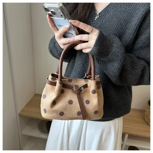 Detailopname van een bruine polkadot emmertas met een lederen handvat en een stijlvolle gesp.