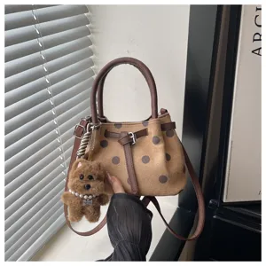 Gedetailleerd overzicht van stijlvolle polkadot emmertas met bruine handvat en pluche hanger.