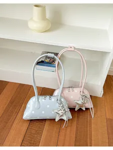 Glossy leather texture detail of the cute polka dot shell bag with star charm and long handles.
