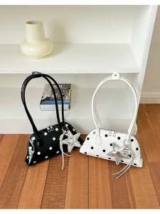 Close-up detail shot of stylish patent leather polka dot shoulder bags with star charms.