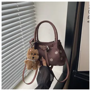 Gedetailleerd overzicht van bruine polkadot emmertas met gesp en schattige pluche hondenhangers.
