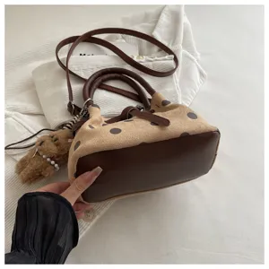 Gedetailleerd overzicht retro polkadot emmertas met bruine lederen afwerking en berenhanger.