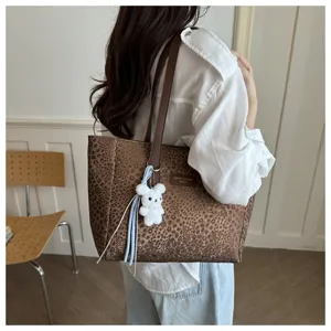 Vue détaillée du sac cabas imprimé léopard avec pendentif lapin en peluche et bandoulière.