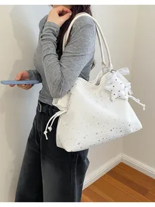 Close-up detail of the white star-patterned tote bag with a cute lace star pendant and straps.