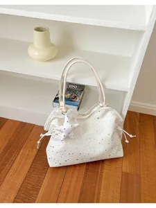 Close-up detail of white star pattern tote bag with cute pendant and side drawstrings.