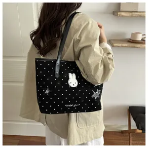 Vue détaillée du sac cabas en toile à pois noirs avec patch lapin mignon et poignées en cuir élégantes.