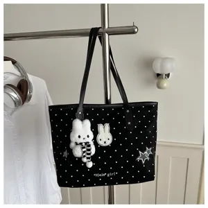 Vue en gros plan du sac cabas à pois noirs avec joli pendentif lapin en peluche et broderie détaillée.