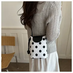 Primo piano dettaglio di una chic borsa porta cellulare a pois neri e bianchi con patta.