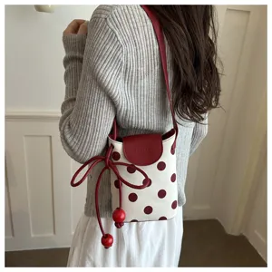 Vista posteriore dettagliata di una borsa per cellulare a pois con tracolla rossa.