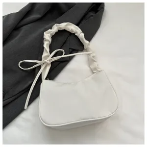 Vista dettagliata di un'elegante borsa a spalla bianca con tracolla arricciata e fiocco carino.