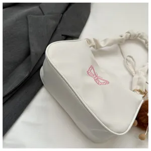 Primo piano dettagliato della elegante borsa a tracolla bianca con ricamo di farfalla.
