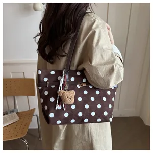 Vista dettagliata della borsa tote marrone a pois in camoscio con ciondolo a orsetto e tracolla.