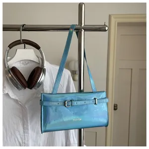 Detail view of the light blue holographic underarm shoulder bag with sleek buckle accent.