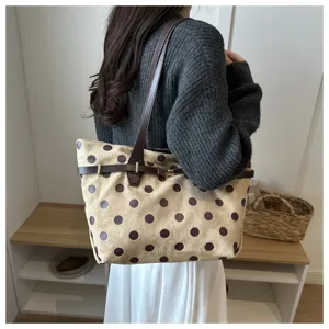 Dettaglio della borsa tote in camoscio marrone con pois e cinturino decorativo molto elegante.
