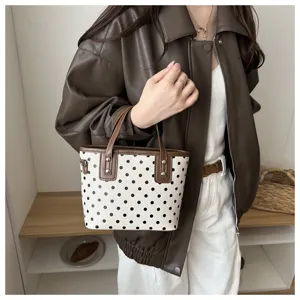 Detailansicht der vintage polka dot eimerhandtasche mit braunen griffen für den täglichen gebrauch.