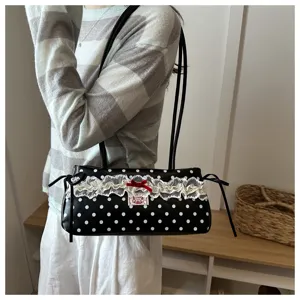 Chic black and white polka dot shoulder bag with delicate white lace trim and red bow accent.