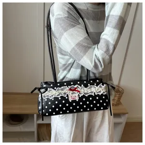 Detailed shot of a black and white polka dot shoulder bag with delicate lace trim.