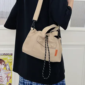 Casual beige canvas crossbody handbag with top handles and front pocket detail for women.