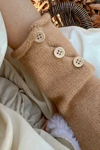 Detalle de guantes de punto cálidos para mujer en color camello con bonitos botones de madera.