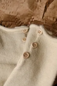 Primer plano detallado de guantes de invierno de punto grueso con botones de madera.
