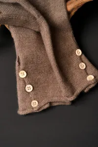 Detalle de calentadores de brazo de punto marrón, textura suave, botones de madera.
