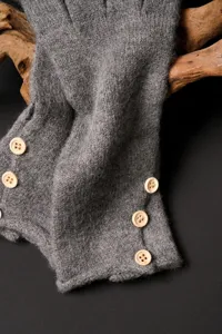 Guantes de invierno de punto gris grueso para mujer en primer plano con botones de madera.