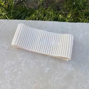 Nahaufnahme des weißen Strick-Wollstirnbandes mit weicher Textur und gotischer Stickerei.