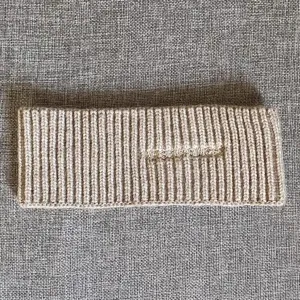Gestricktes Stirnband mit feiner Stickerei, weiche Textur und bequeme Passform für den Alltag.