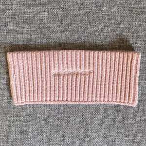 Rosa Strickstirnband mit gesticktem Buchstaben Detail, ein warmes Damenhaaraccessoire.