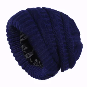 Detailed close-up view of dark blue cable knit beanie with smooth black satin inner lining.