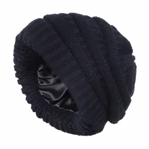 Detail view of a black satin-lined knit beanie, warm windproof slouchy winter hat.