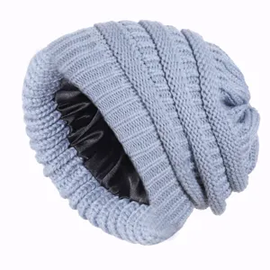 Detail close-up of the grey knitted beanie showcasing the smooth black satin inner lining.
