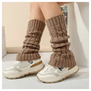 Nahaufnahme gemütlicher brauner Zopfstrick-Beinwärmer über Sneakers für Herbst und Winter.