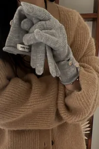 Detalle de guantes de punto gris, guantes de invierno cálidos para mujer con botones y textura.