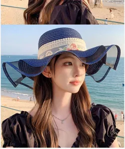 Détail chapeau de soleil plage, large bord en filet et ruban de dentelle, style vacances.