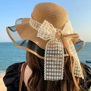 Vue détaillée de l'élégant chapeau de paille de plage avec grand nœud en dentelle.
