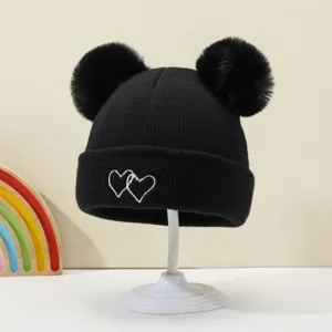 Cute baby black knit hat with double pom poms and white heart embroidery for warmth.