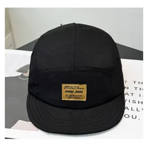 Detailansicht einer schwarzen 5-Panel-Cap mit kurzem, weichem Schirm und gewebtem Label.