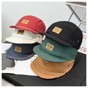 Detailaufnahme mehrfarbiger 5-Panel-Caps mit kurzen Schirmen und gewebten Patches im Alltag.