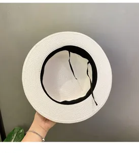 Detailed view of a white straw sun hat with black inner band, casual beach wear.