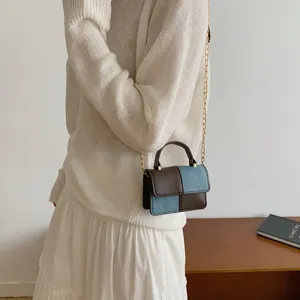 Detailed view of the stylish color-blocked shoulder bag with chain strap and patchwork design.