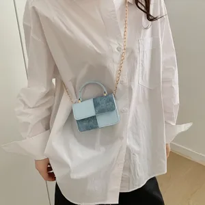 Detail view of a stylish patchwork mini crossbody bag with chic chain strap and handle.