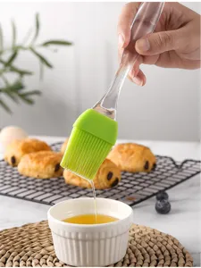 Detail shot of silicone oil brush with clear handle dripping oil for baking and BBQ use.