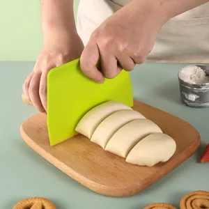 Kunststof deegschraper om te bakken, trapezefvormige deegsnijder en taartsnijder op houten plank.
