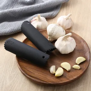Black silicone garlic peeler kitchen tool with wooden plate and fresh garlic cloves for easy peeling.